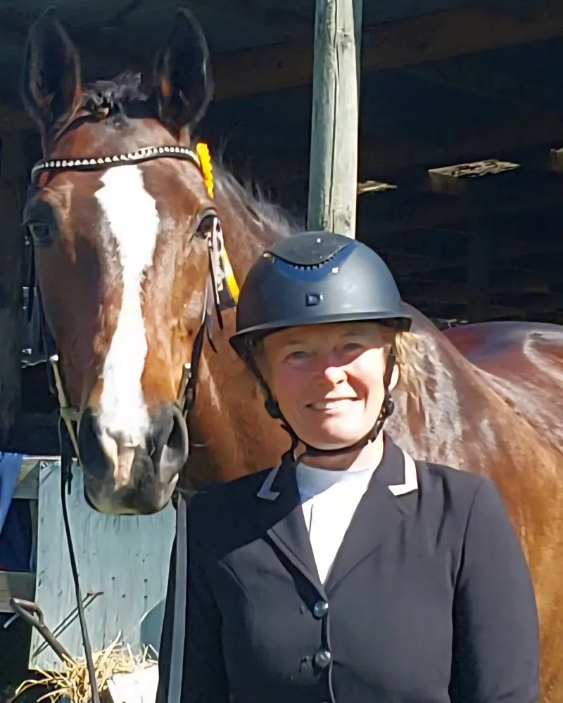 Rebecca standing with her bay horse, wearing her show jacket